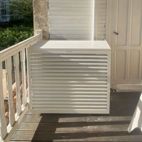 Cache-climatiseur blanc design en aluminium pour extérieur Cache-climatiseur blanc en aluminium sur un balcon en bois. Texte : AIR ENCLOSURE. Design moderne et épuré.