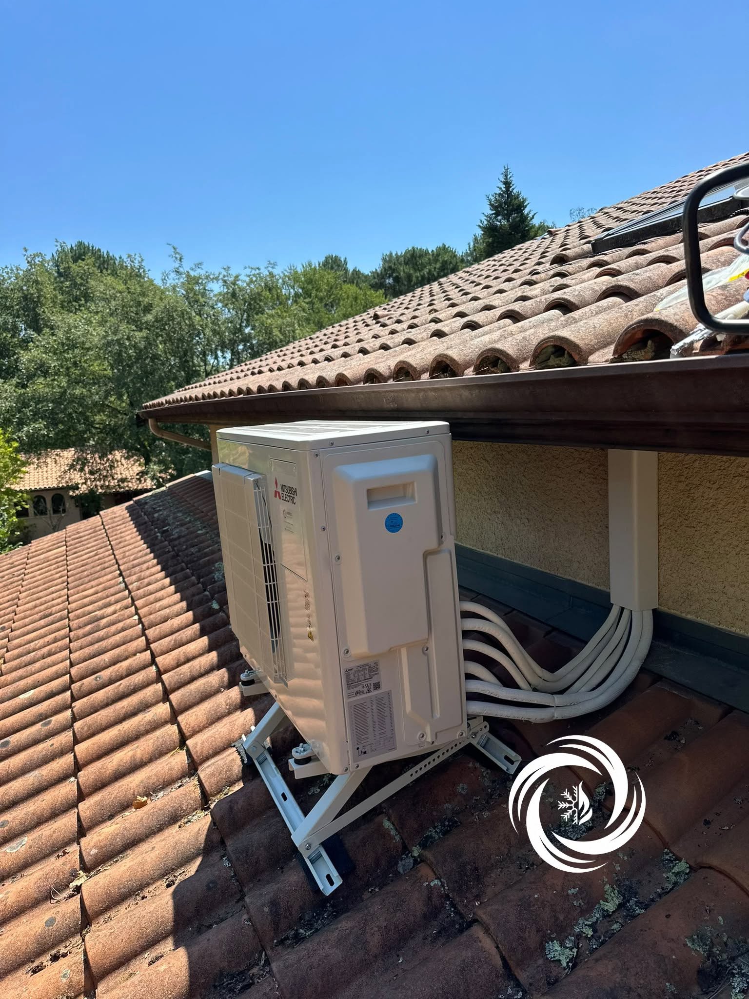 Climatisation Mitsubishi Electric : Installation sur Toit Climatiseur Mitsubishi Electric sur toit en tuiles avec support blanc et conduits isolés.