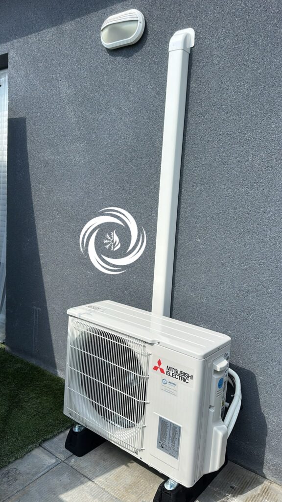 Unité Mitsubishi Electric installée sur mur gris avec conduit blanc et logo chauffage/climatisation.