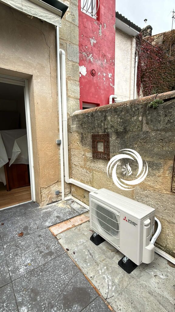 Climatiseur Mitsubishi Electric sur mur extérieur en pierre.