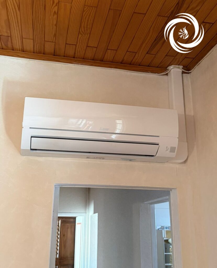 Climatiseur mural Mitsubishi blanc, installation avec goulotte sous plafond bois.