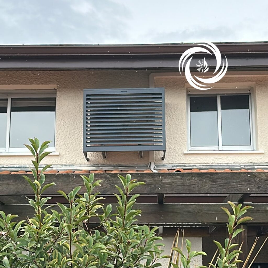 Cache-clim gris anthracite à lamelles installé sur une façade entre deux fenêtres au-dessus d'une pergola.